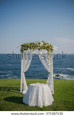 wedding ceremony flowers, arch, chairs with black sea in the background