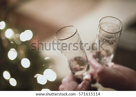 happy new year toast with a christmas tree lights in background Royalty-Free Stock Photo #571615114