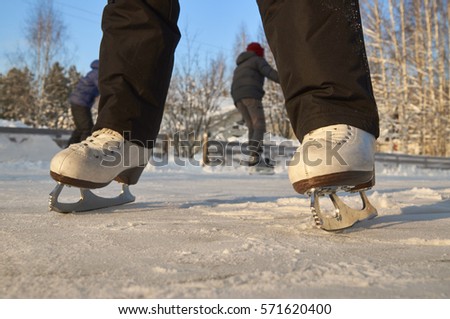 Feet of girl wearing skates on ice rink                            