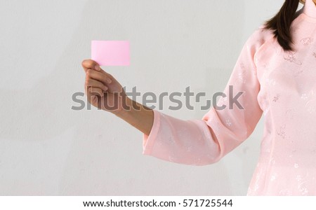 Woman beautiful pink dress hands holding a pink business visit card on white background.