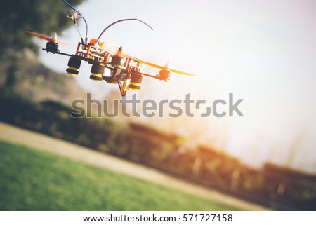 A colorful drone flying over the park on a sunset at horizon on blurred background - Innovation photography concept - Technology merged with nature