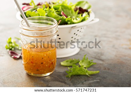 Italian vinaigrette dressing in a mason jar with fresh vegetables on the table Royalty-Free Stock Photo #571747231