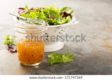 Italian vinaigrette dressing in a mason jar with fresh vegetables on the table Royalty-Free Stock Photo #571747369