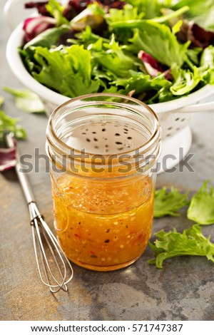 Italian vinaigrette dressing in a mason jar with fresh vegetables on the table Royalty-Free Stock Photo #571747387