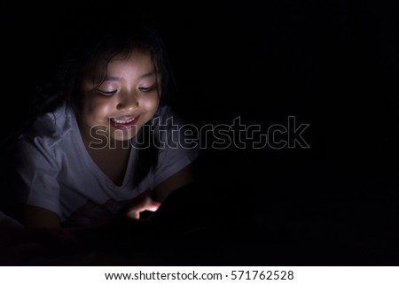 Kid with tablet sitting on bed and watching cartoons at night.
