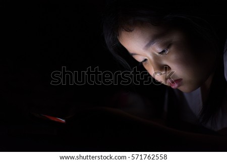 Kid with tablet sitting on bed and watching cartoons at night.