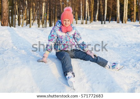 cheerful girl with skates on his feet sitting on the snow