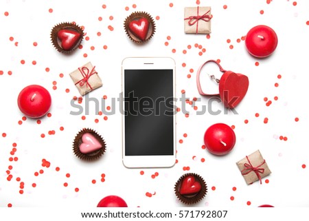 Styled Valentines Day flatlay top view. Smartphone, sweets, presents, candles, box with proposal ring  and confetti on white. Holiday concept. Copy space for text