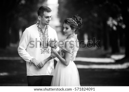 Black and white picture of young wedding couple standing in the forest
