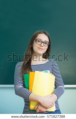 beautiful, cute, smart, intelligent, cheerful girl student sitting at a desk in a bright room school