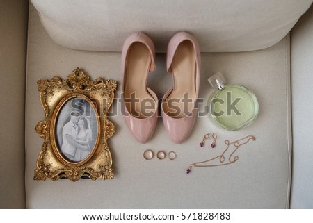 Wedding accessories: photo frame with bride and groom portrait, bridal shoes, perfume bottle, jewelry and wedding and engagement rings