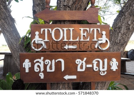 Symbol of toilet in thai language and english language on wood