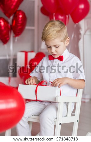 Cute boy with a gift on a background of hearts. Valentine's Day.
