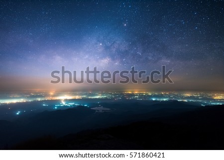 Night landscape of Milky way above the light of countryside area and mountain. Royalty-Free Stock Photo #571860421