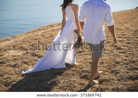 Beautiful young couple walks along the ocean at sunset.
