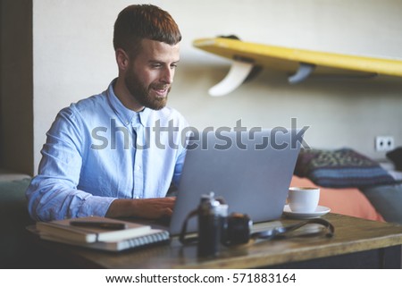Handsome bearded male entrepreneur making remate job cooperating with colleague in online chat planning strategy for new startup project while keyboarding on laptop computer connected to 5G wireless