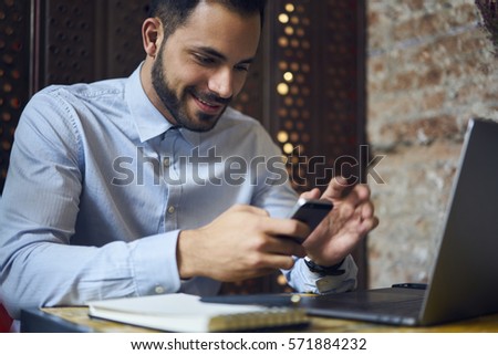 Portrait of talented well dressed executive manager doing remote job while checking email box waiting for bank confirmation paying bills using smartphone connected to wireless internet in cafe