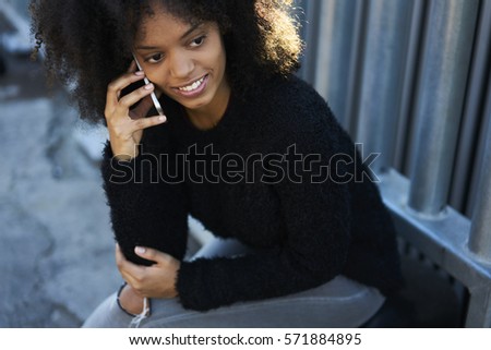 Attractive young female afro American creative manager of company having phone conversation with colleague talking about working plan while being in trip on holiday using free 5G wireless in wifi zone