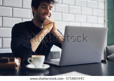 Talented male editor of popular magazine starting working day monitoring morning news on websites choosing main theme for front page using modern laptop computer and wireless connection to internet Royalty-Free Stock Photo #571885441