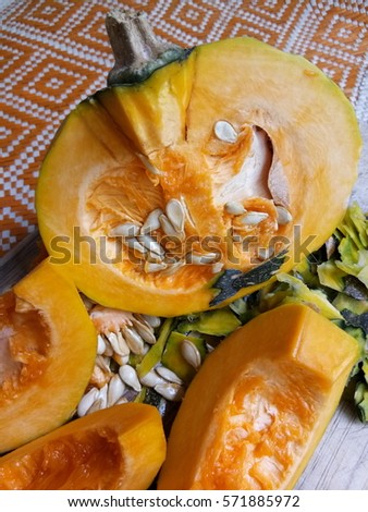 Slice pumpkins with seeds on wood and on traditional mat.
