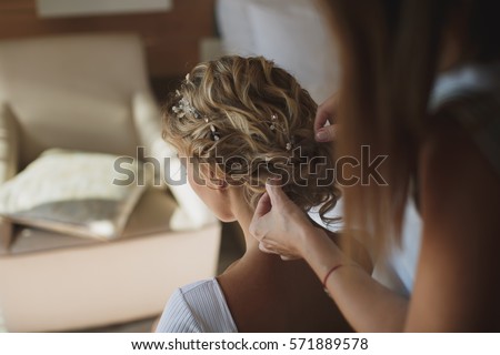 Stylist makes hair the bride Royalty-Free Stock Photo #571889578