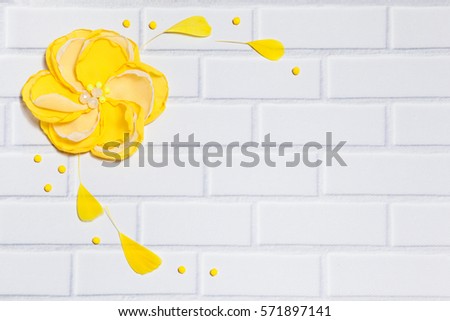 White Background With Handmade Gentle Yellow Flower and Feathers, Lying Flat on the White Brick Wall, Top View. Have an Empty Place For Your Text.