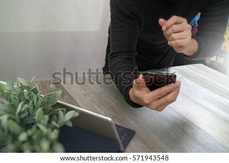 Businessman hand using mobile payments online shopping,omni channel,in modern office wooden desk,icons graphic interface screen,eyeglass