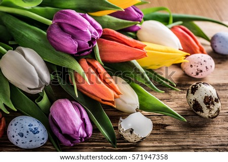 Colorful tulips with quail eggs on old wooden background. Spring and Easter concept with copy space. Retro style toned.