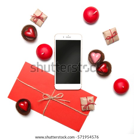 Minimal styled Valentine's Day flatlay top view isolated on white. Sweet hearts, gifts in craft paper, smartphone mockup, candles, red envelope. Love concept