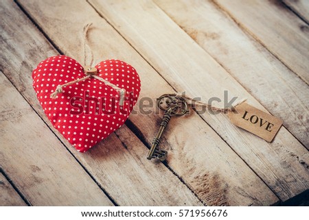 Heart fabric and vintage key with tag label LOVE on wood table background.