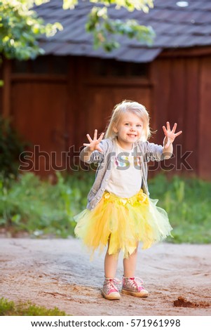 little blonde  child girl  3 years in a tutu skirt standing on the street in the  skirt tutu