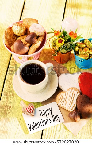 Heart shaped cookies (big and small as couple), cup of coffee, bouquet of flowers decoration on yellow table. sunny morning. Romantic breakfast or Valentine's Day Breakfast. Toned imag