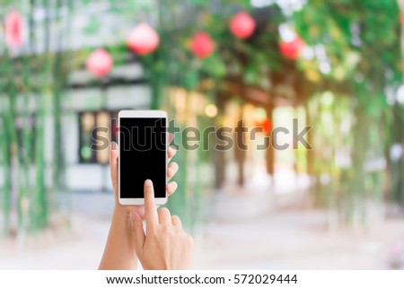 woman use mobile phone and blurred image of Chinese house around with green bamboo