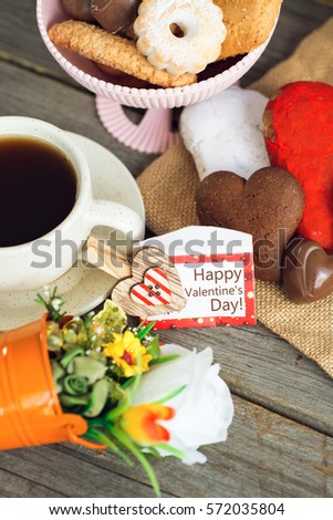 Heart shaped cookies and chocolate candies (big and small as couple), cup of coffee, bouquet of flowers decoration. sunny morning. Romantic breakfast or Valentine's Day Breakfast. Toned image 