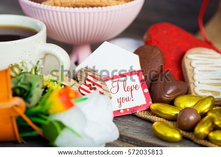 Heart shaped cookies and chocolate candies (big and small as couple), cup of coffee, bouquet of flowers decoration. sunny morning. Romantic breakfast or Valentine's Day Breakfast. Toned image 
