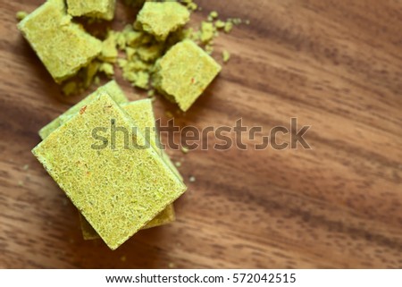 Vegetable bouillon, stock or broth cubes piled on wooden plate, photographed overhead with natural light (Selective Focus, Focus on the top cube)