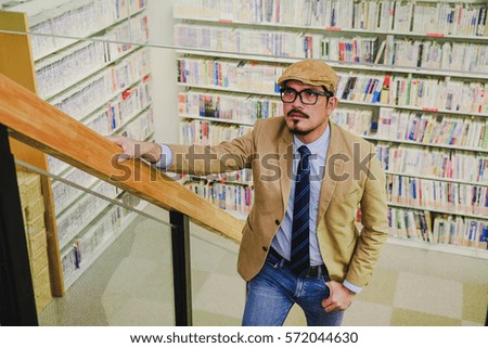 Smart business man with spectacle over staircase background bookcase.