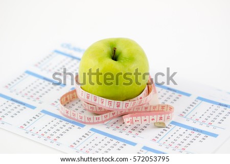 Blurred image. Fresh green apples with measuring tape and calendar concept of weight loss Isolated on a white background.