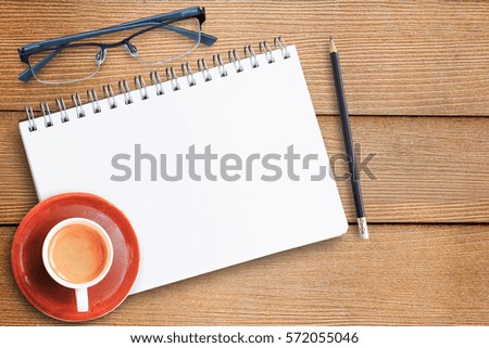 Top view with notebook,glasses,pencil and cup of coffee on office desk