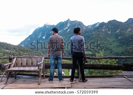 Asian man couple looking at the beautiful sunrise on the top of mountain with the view into misty.