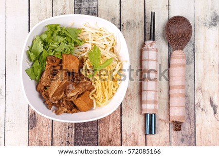Steam duck and noodle in brown sauce on wood.