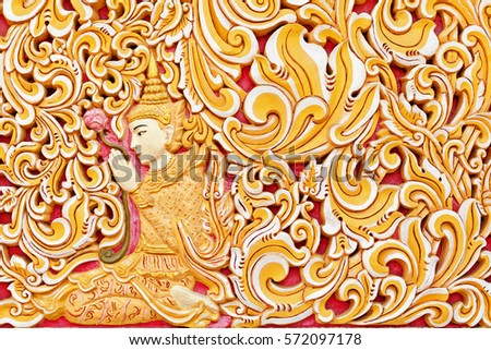 Wall exterior detail of ancient Burmese buddhist temple Dhammikarama in Georgetown on Penang island. Sitting in meditating pose Buddha hold in hand lotus flower. Asian arts, culture. Travel background