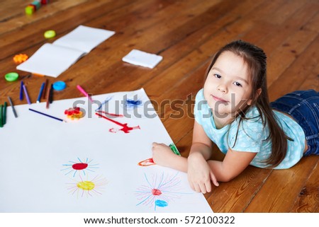 preschool girl drawing on a large sheet of white paper