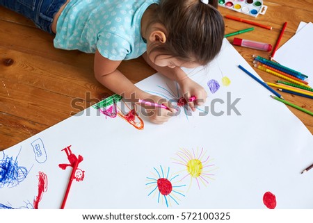 girl drawing on a large sheet of white paper