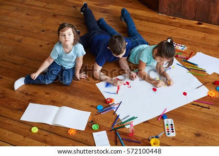 three children drawing together on the floor