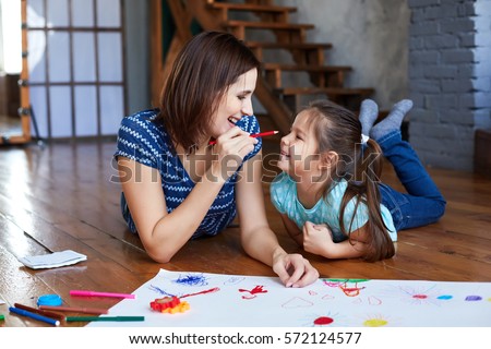 Mother and daughter drawing together. Mother and daughter having fun