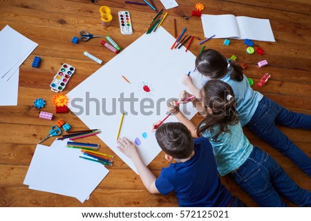 children draw together on a large sheet of paper