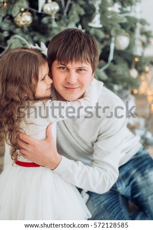 Happy little girl with father near Christmas tree