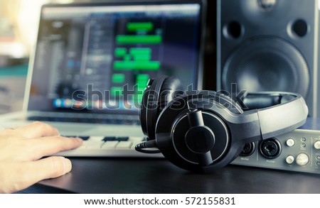 Sound engineer is working on his home music work station mixing Audio sound on a song on his laptop DAW station and headphone.