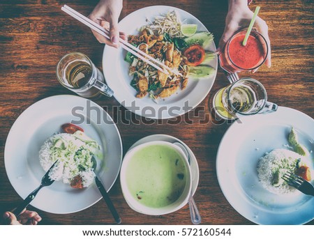 Group of people having dinner at the table. The picture above. Thai - padtay and green curry